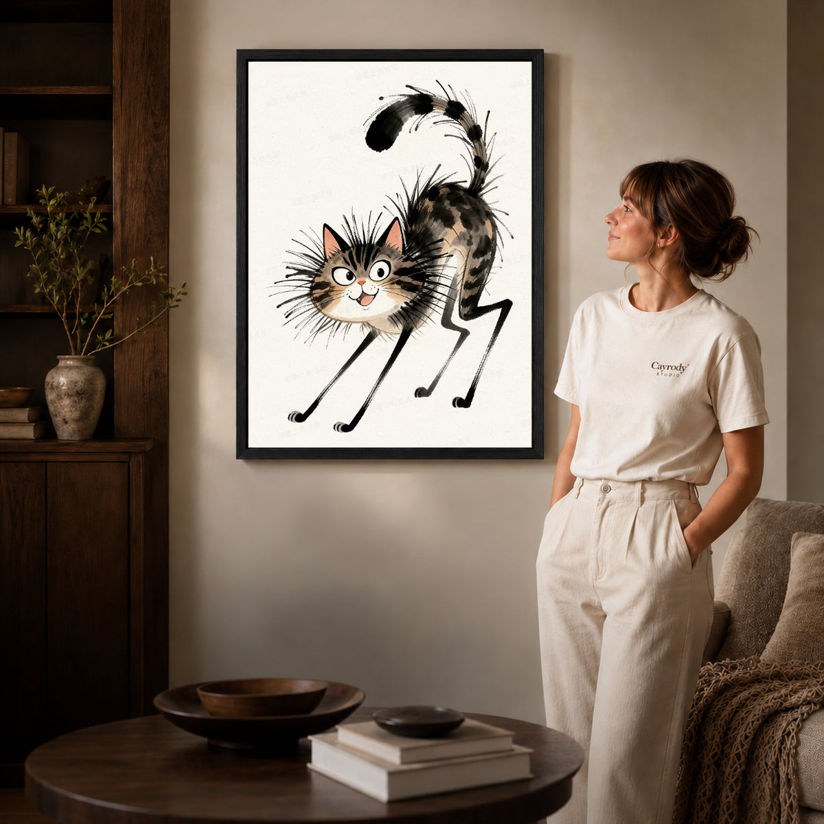 Tabby Cat Canvas Art inside a black frame in a softly lit living room with books.