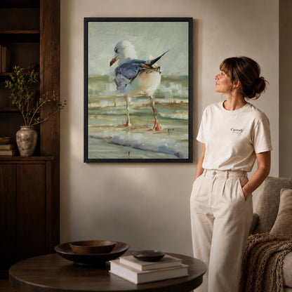 Seagull Canvas Art inside a black frame in a softly lit living room with books.