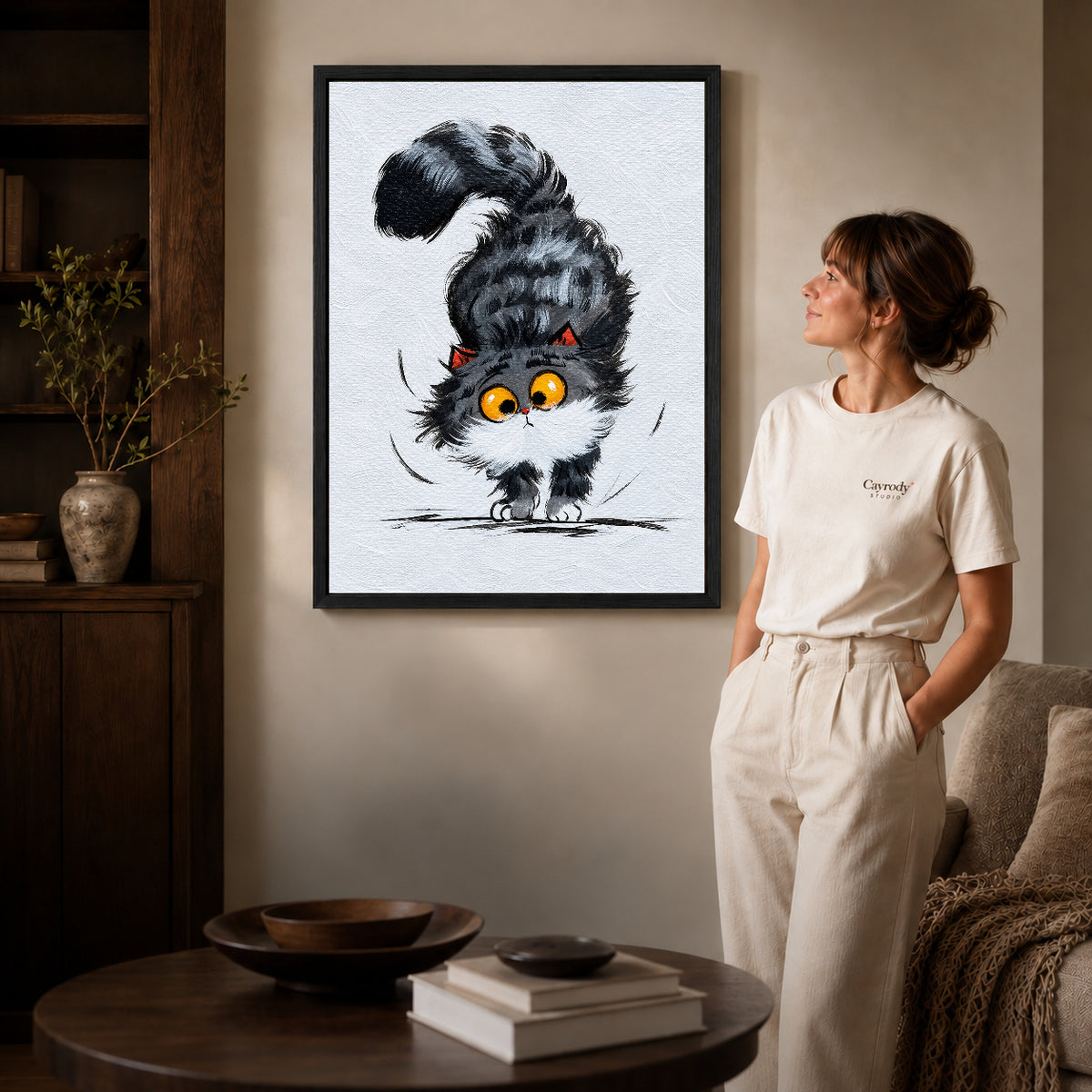 Kitten Canvas Wall Art inside a black frame in a softly lit living room with books.
