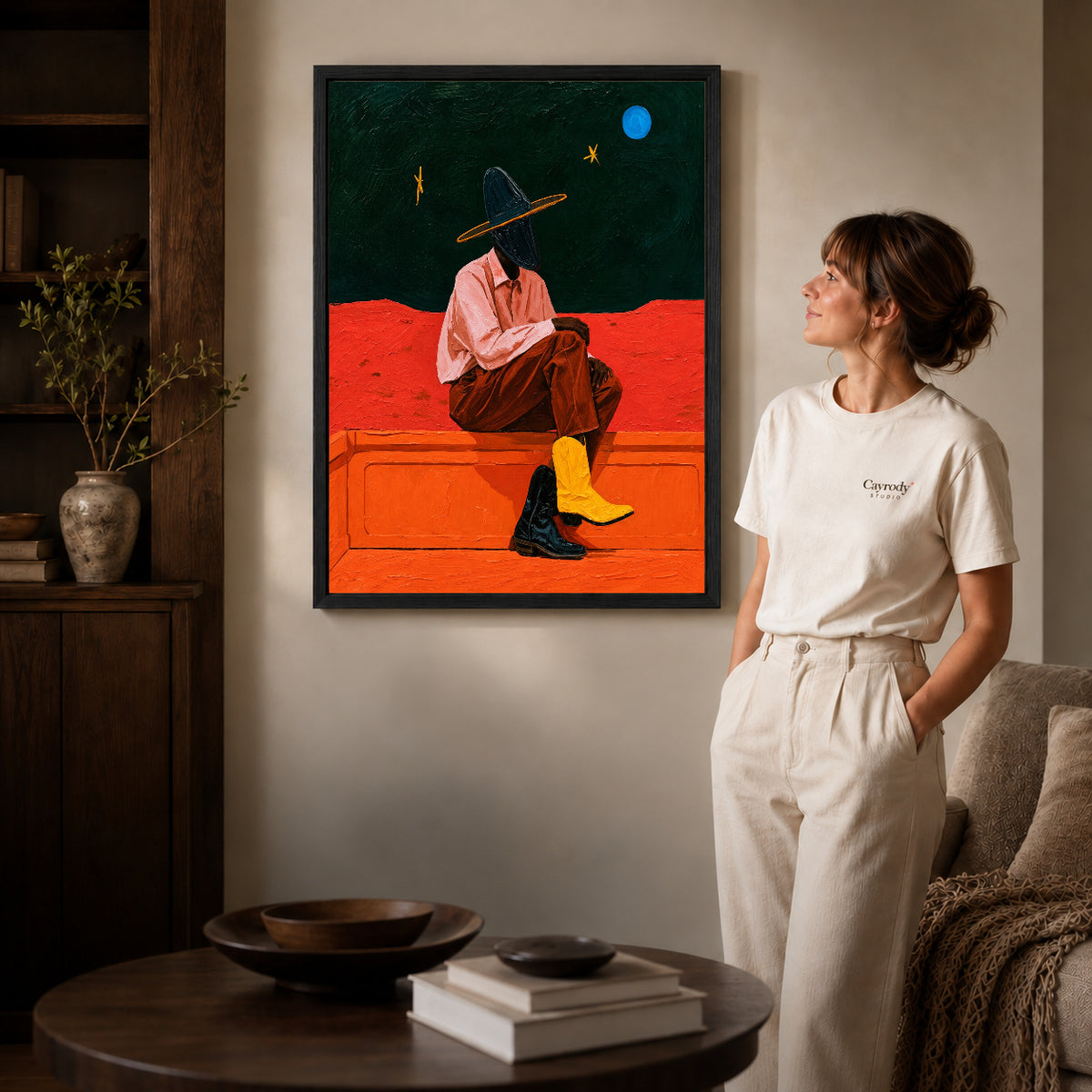 Cowgirl Canvas Wall Art inside a black frame in a softly lit living room with books.