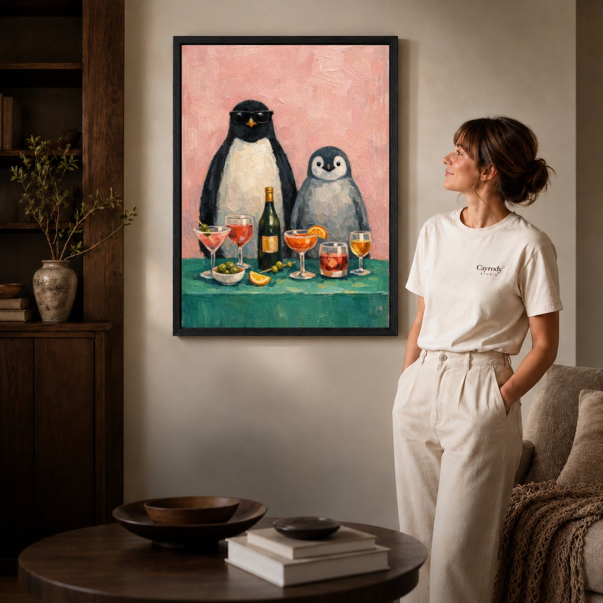Penguin Canvas Wall Art inside a black frame in a softly lit living room with books.