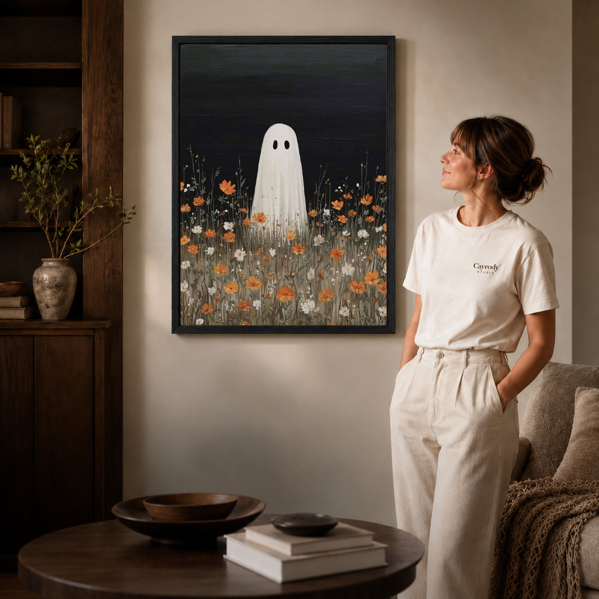 Ghost Canvas Wall Art inside a black frame in a softly lit living room with books.