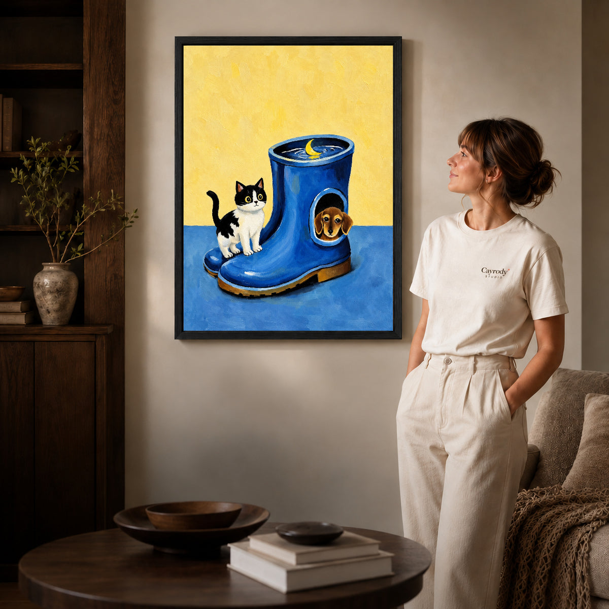 Black framed whimsical pet canvas art displayed beside a woman with natural light across the wall.