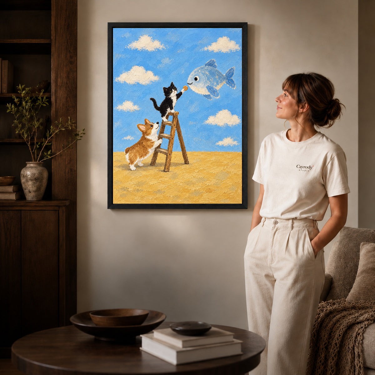 Whimsical Cat Canvas Art inside a black frame in a softly lit living room with books.