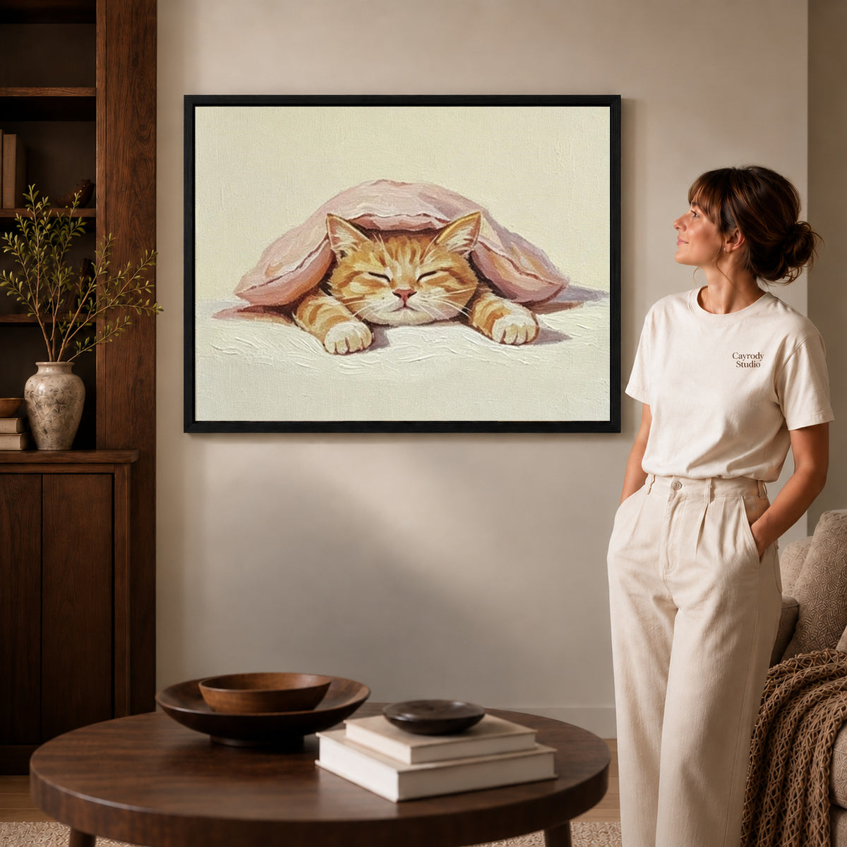 Black framed sleeping cat canvas art displayed beside a woman with natural light across the wall.
