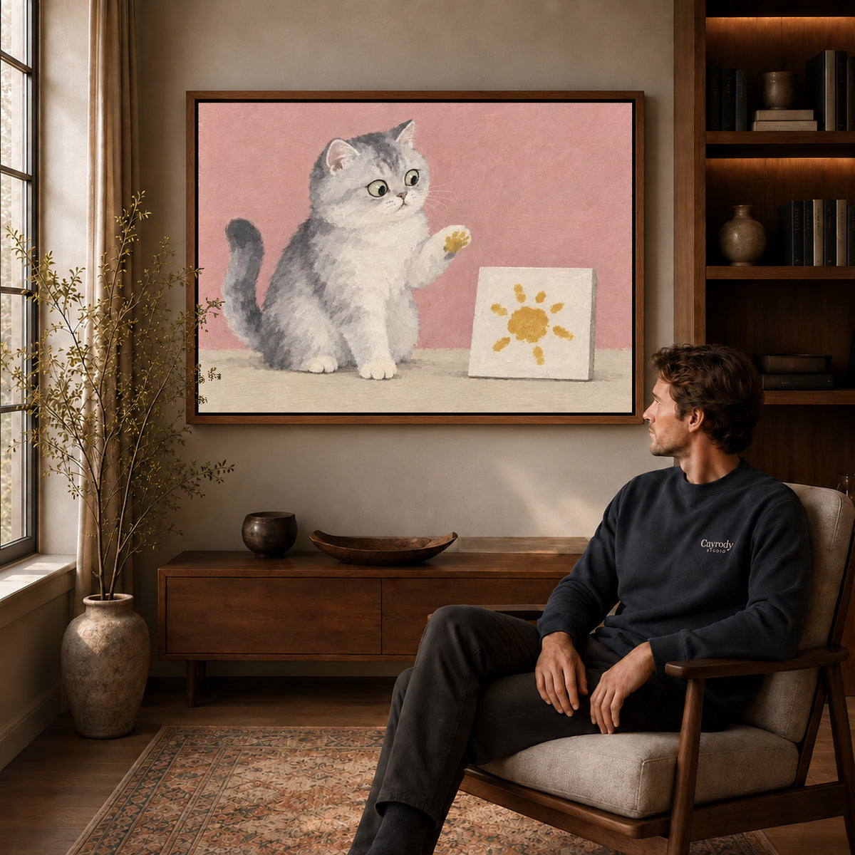 Artist Cat Canvas Art displayed in a walnut frame above wooden furniture beside a seated man.