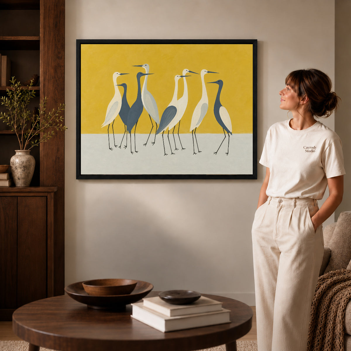 Heron Canvas Wall Art inside a black frame in a softly lit living room with books.