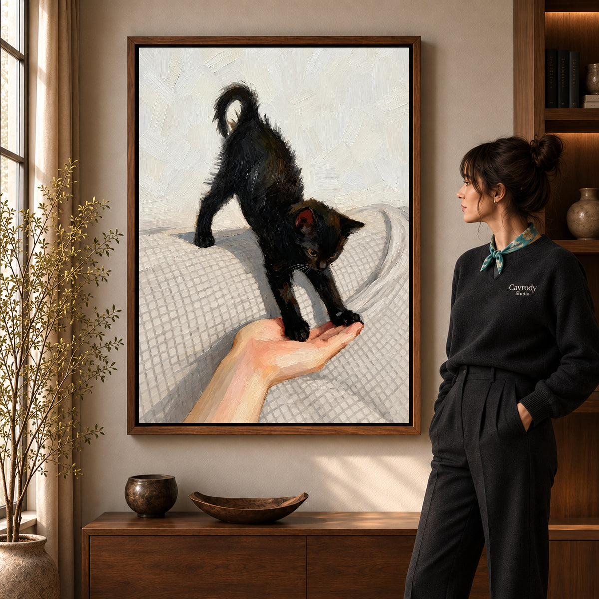 Black Kitten Canvas Art in a walnut frame beside a standing woman and warm wooden furniture.