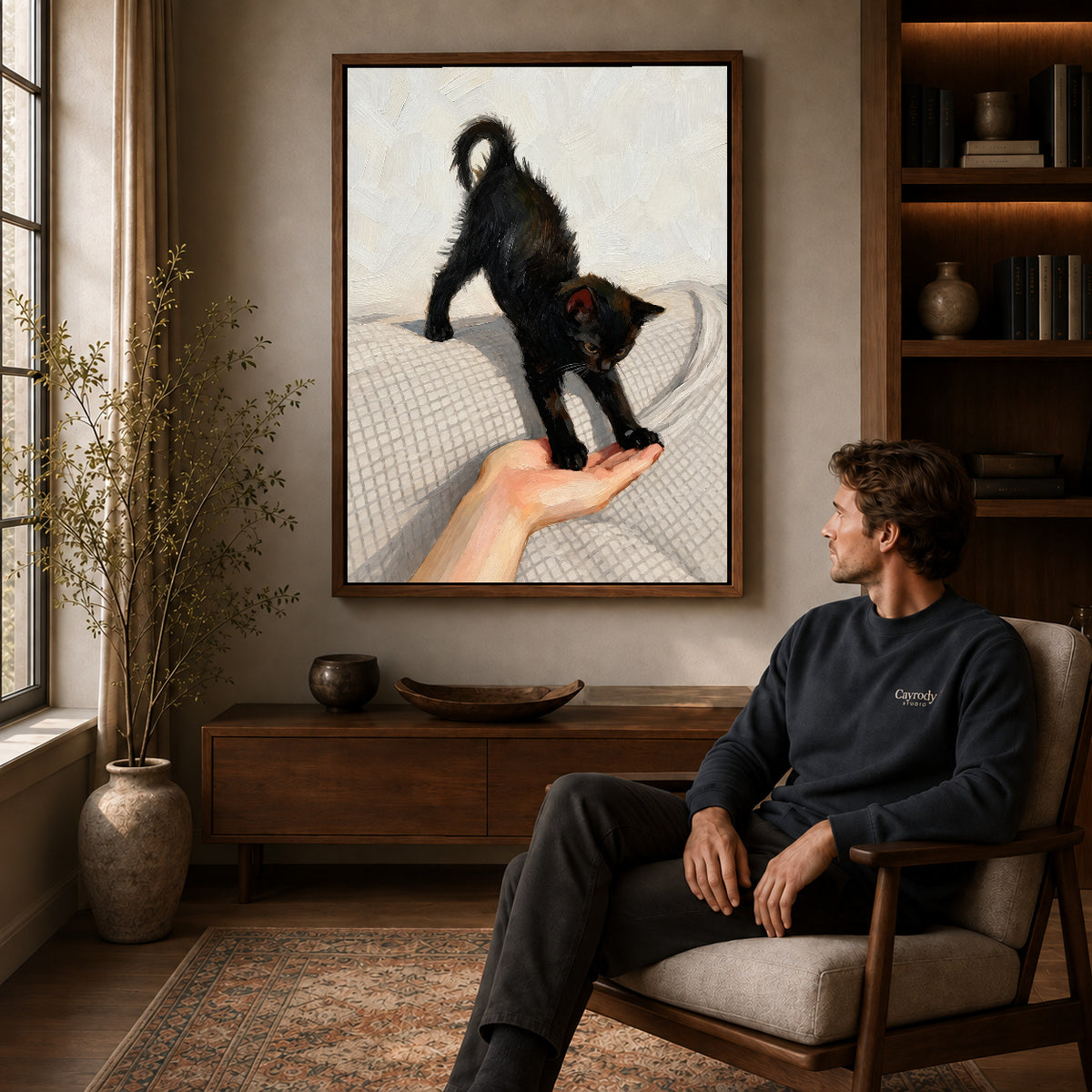 Black Kitten Canvas Art displayed in a walnut frame above wooden furniture beside a seated man.