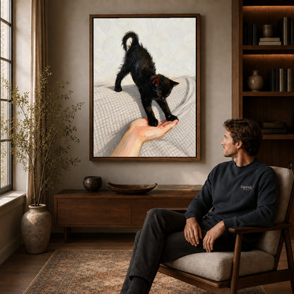 Black Kitten Canvas Art displayed in a walnut frame above wooden furniture beside a seated man.