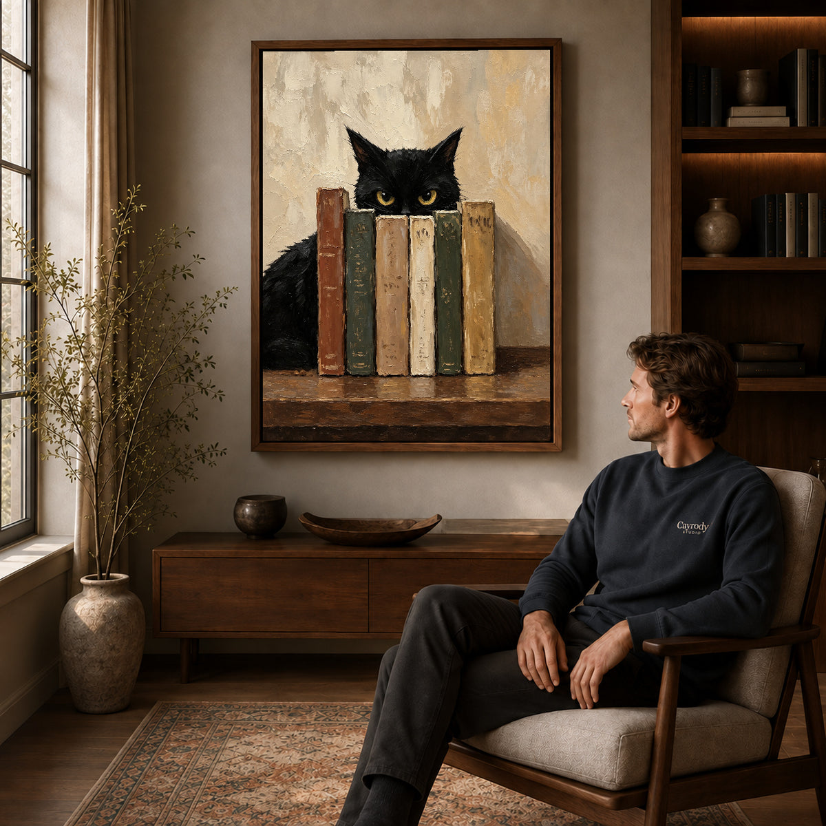 Bookish Cat Canvas Art displayed in a walnut frame above wooden furniture beside a seated man.