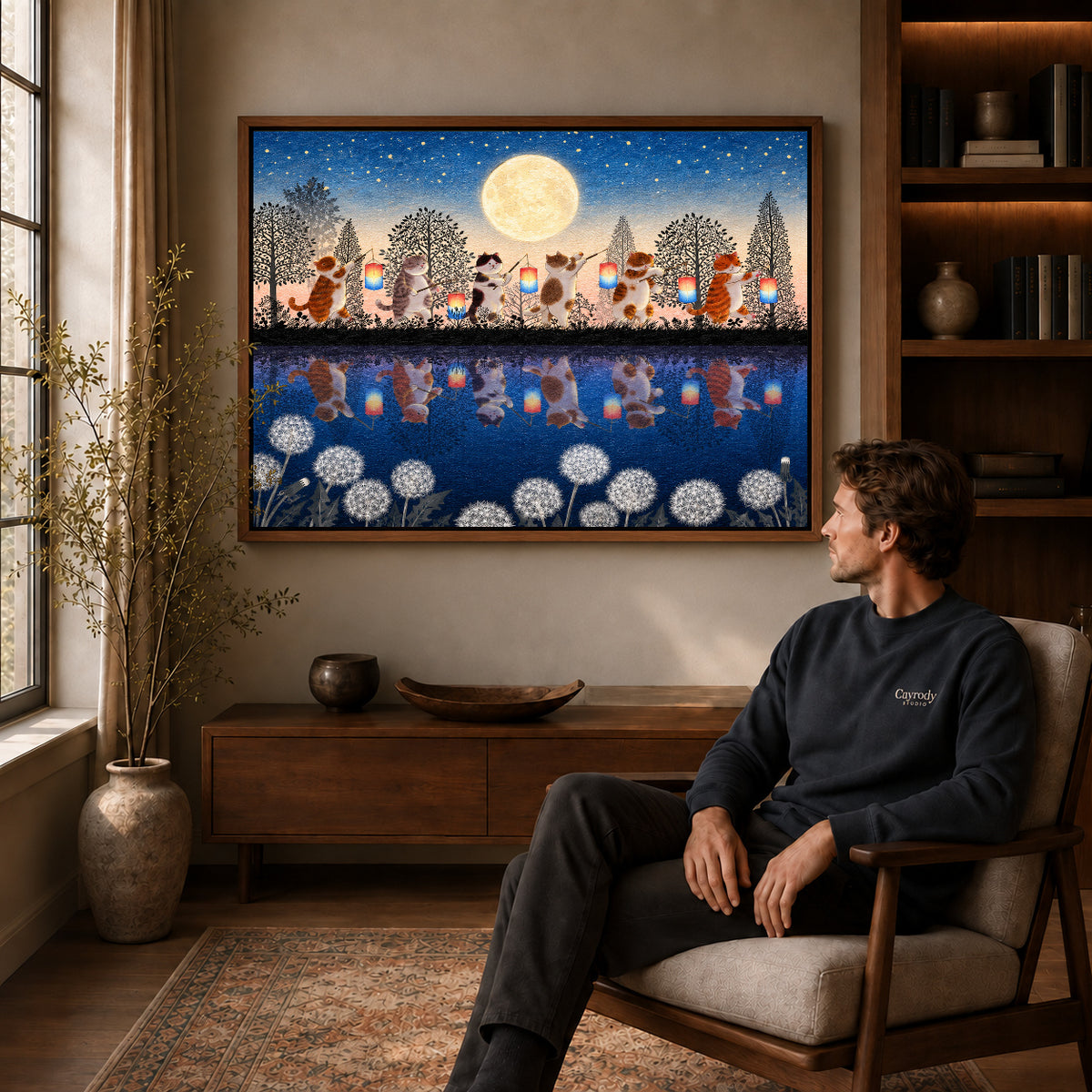 Lantern Cat Canvas Art displayed in a walnut frame above wooden furniture beside a seated man.