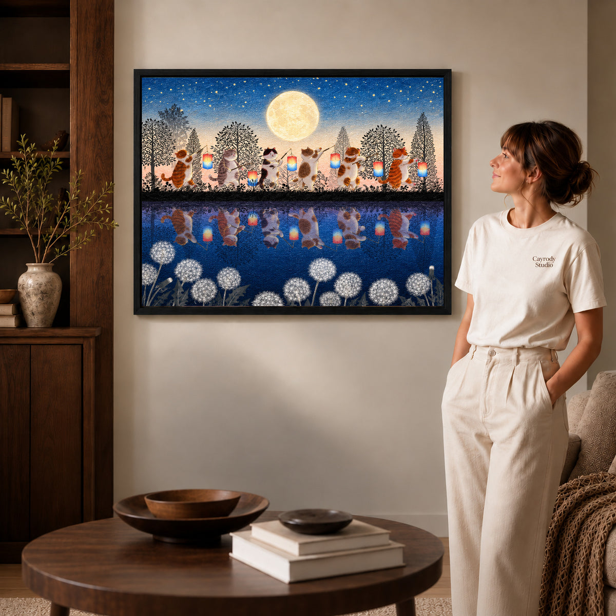 Black framed lantern cat canvas art displayed beside a woman with natural light across the wall.
