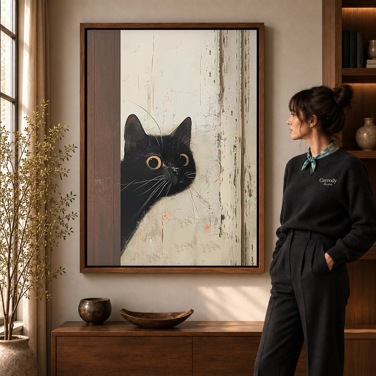 Black Cat Canvas Art in a walnut frame beside a standing woman and warm wooden furniture.