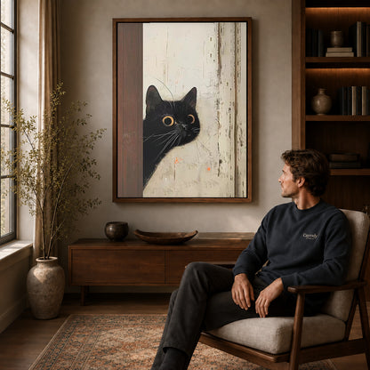 Black Cat Canvas Art displayed in a walnut frame above wooden furniture beside a seated man.