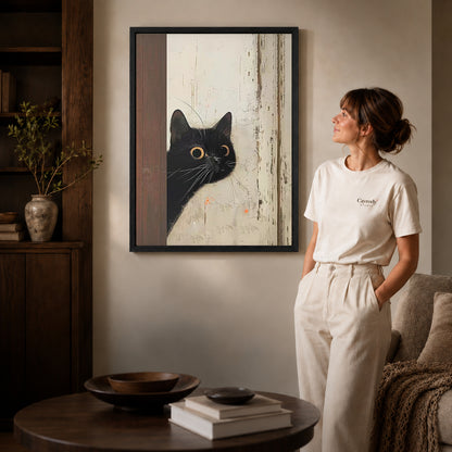 Black Cat Canvas Art inside a black frame in a softly lit living room with books.
