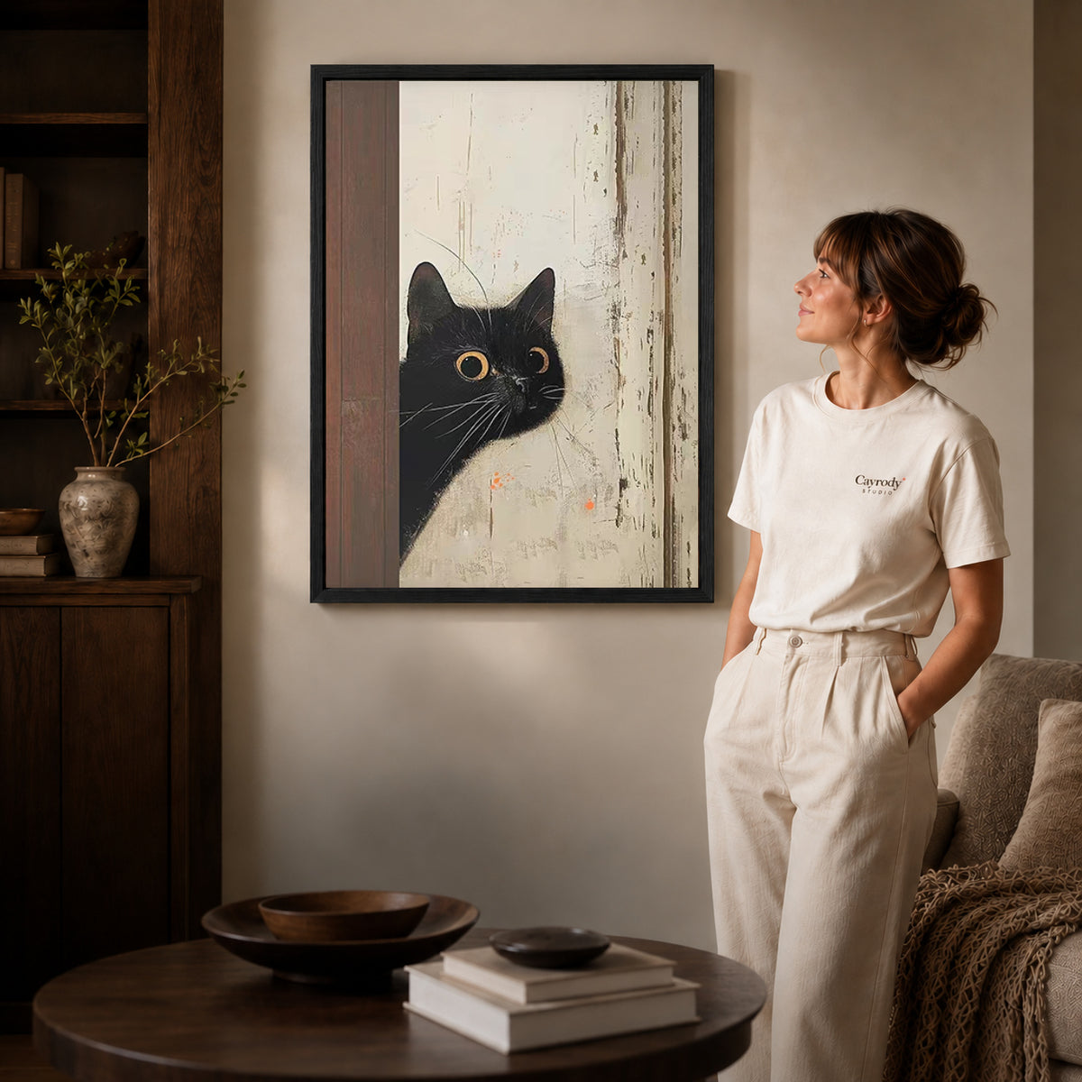 Black framed black cat canvas art displayed beside a woman with natural light across the wall.