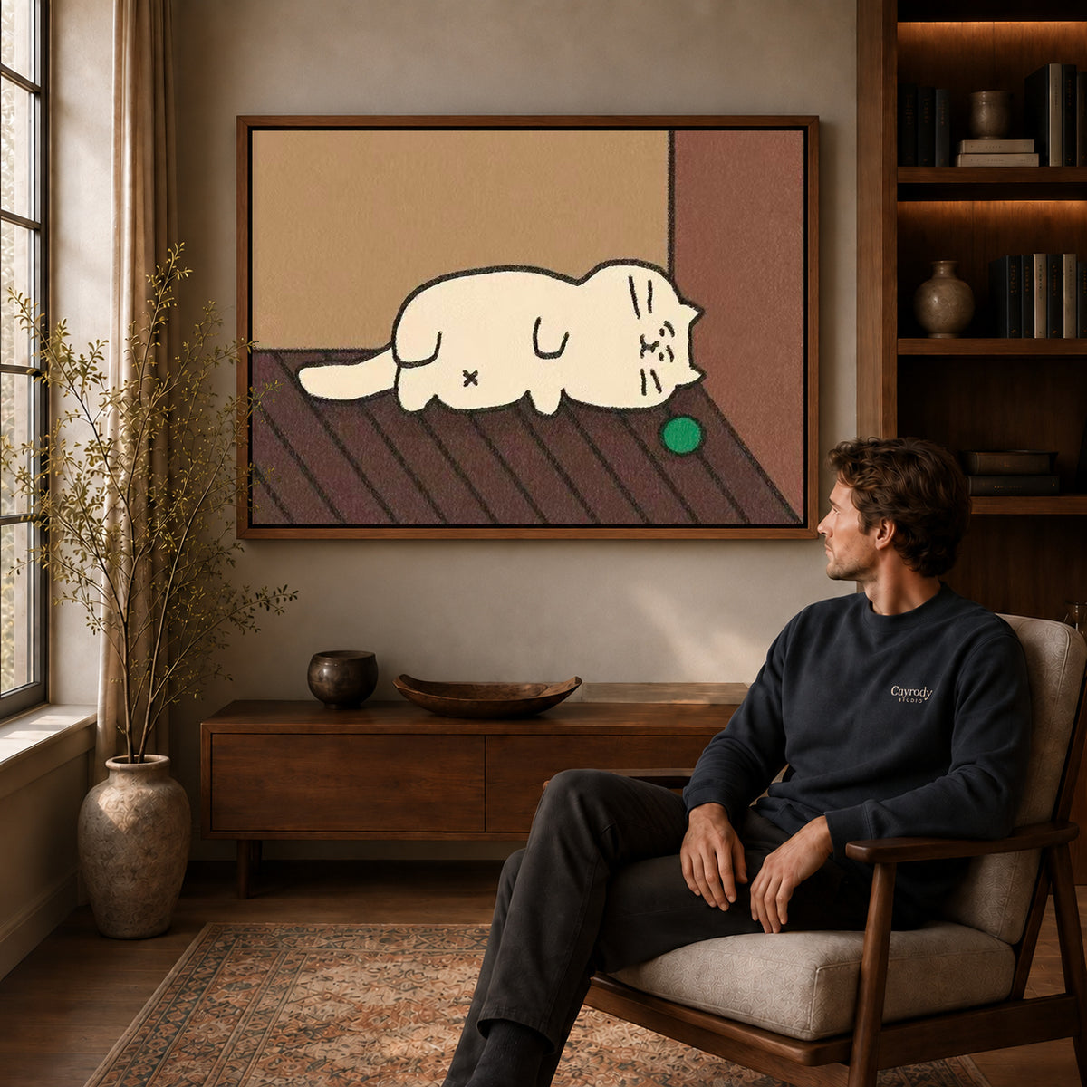 Sleepy Cat Canvas Art displayed in a walnut frame above wooden furniture beside a seated man.