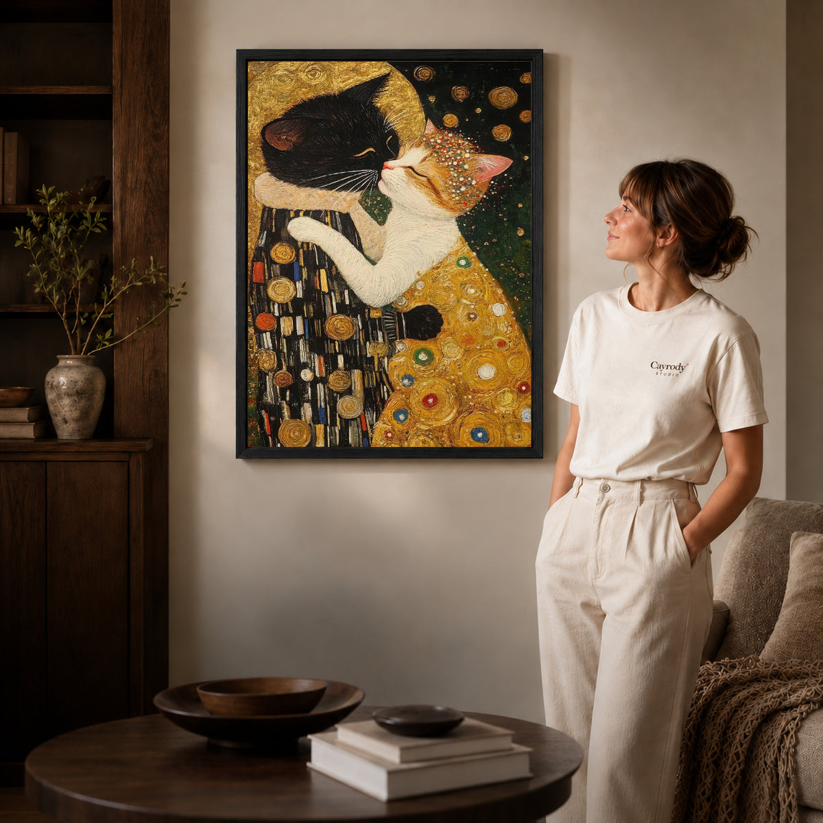 Golden Cat Embrace Canvas Art inside a black frame in a softly lit living room with books.