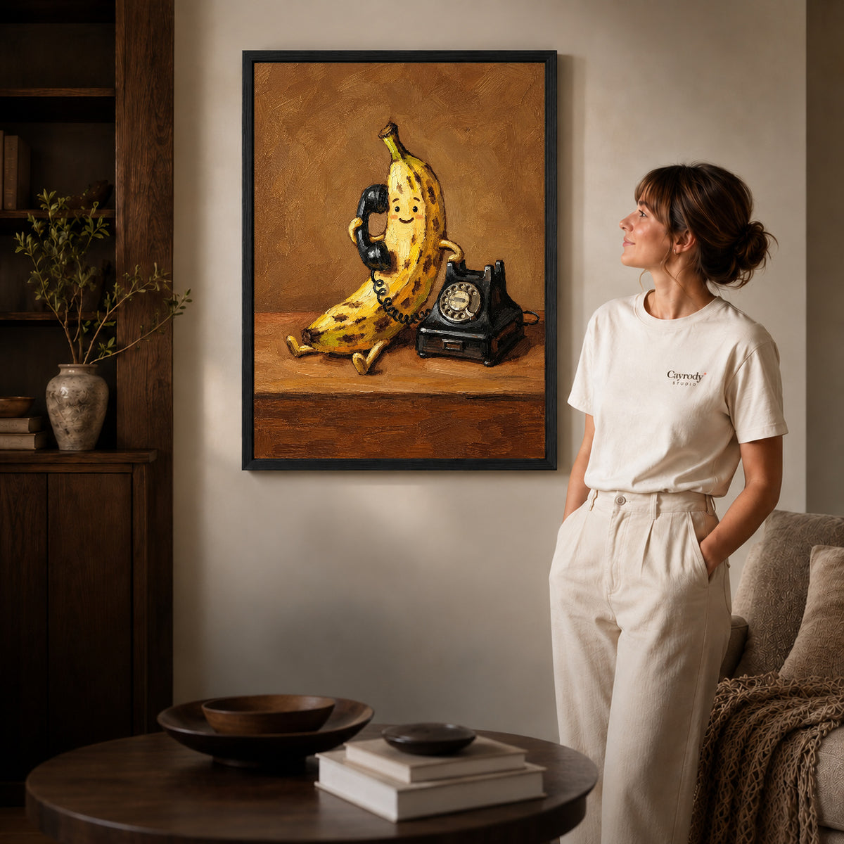 Black framed banana telephone canvas art displayed beside a woman with natural light across the wall.