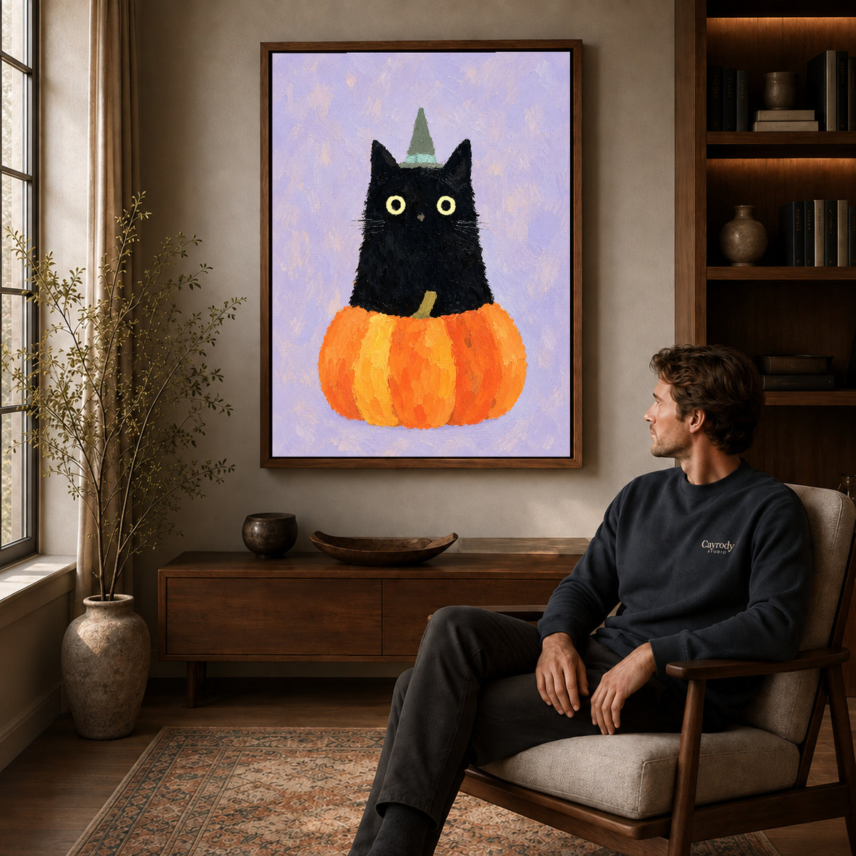 Pumpkin Witch Cat Canvas Art displayed in a walnut frame above wooden furniture beside a seated man.