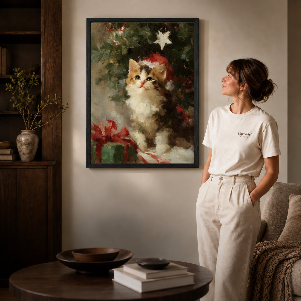 Christmas Kitten Canvas Art inside a black frame in a softly lit living room with books.