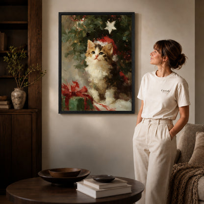 Christmas Kitten Canvas Art inside a black frame in a softly lit living room with books.
