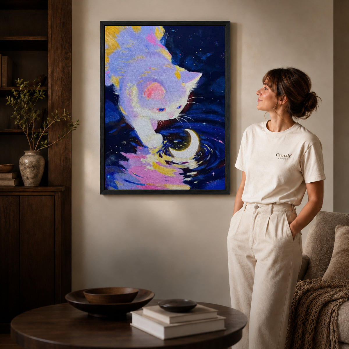 Moonlit Kitten Canvas Art inside a black frame in a softly lit living room with books.