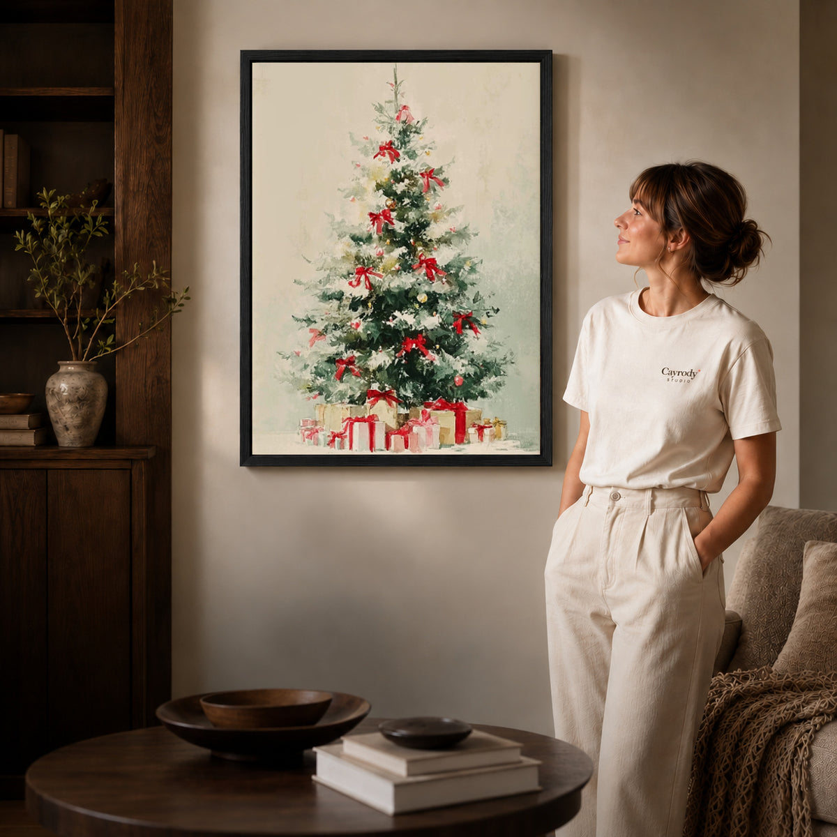 Black framed snowy christmas tree canvas art displayed beside a woman with natural light across the wall.