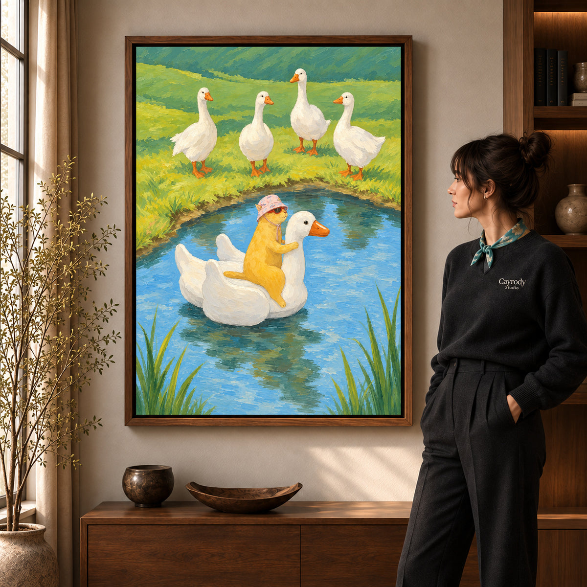 Whimsical cat canvas art in a walnut frame beside a woman in a warm living room.