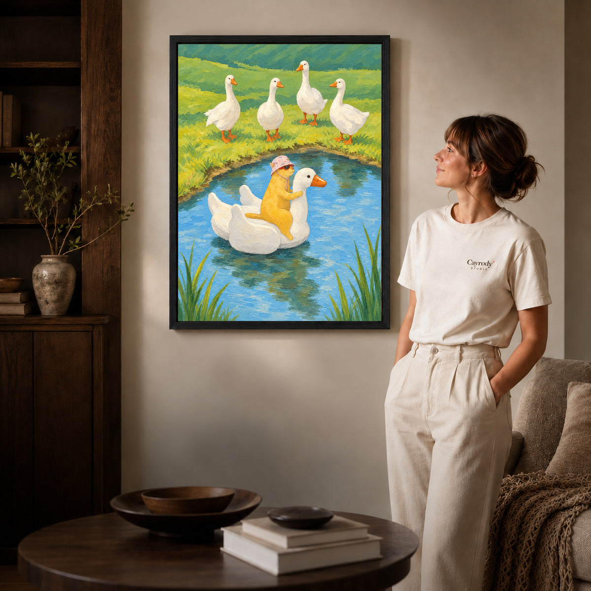 Black framed whimsical cat canvas art displayed beside a woman in a warm wood living room.