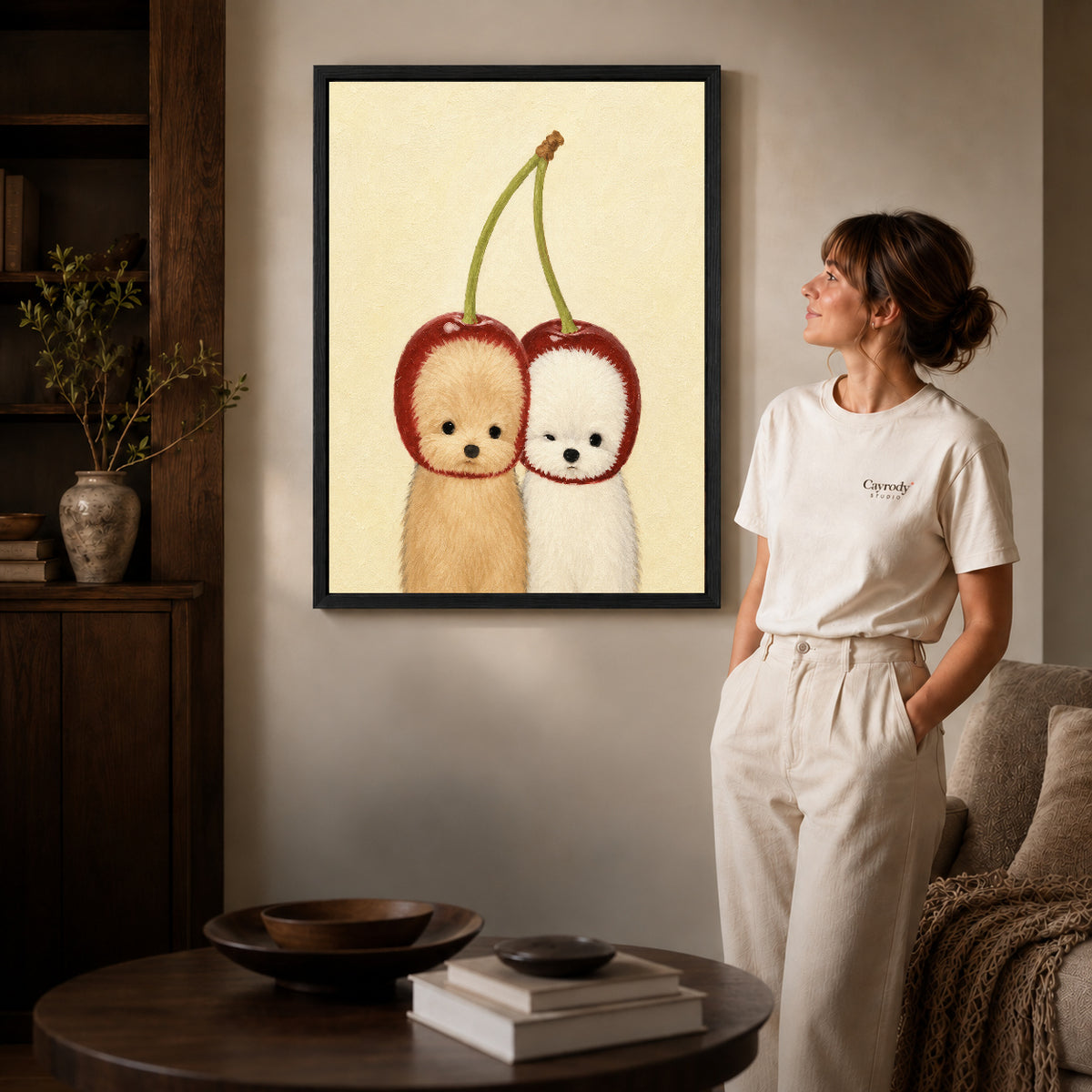 Black framed cherry puppy canvas art displayed beside a woman in a warm wood living room.