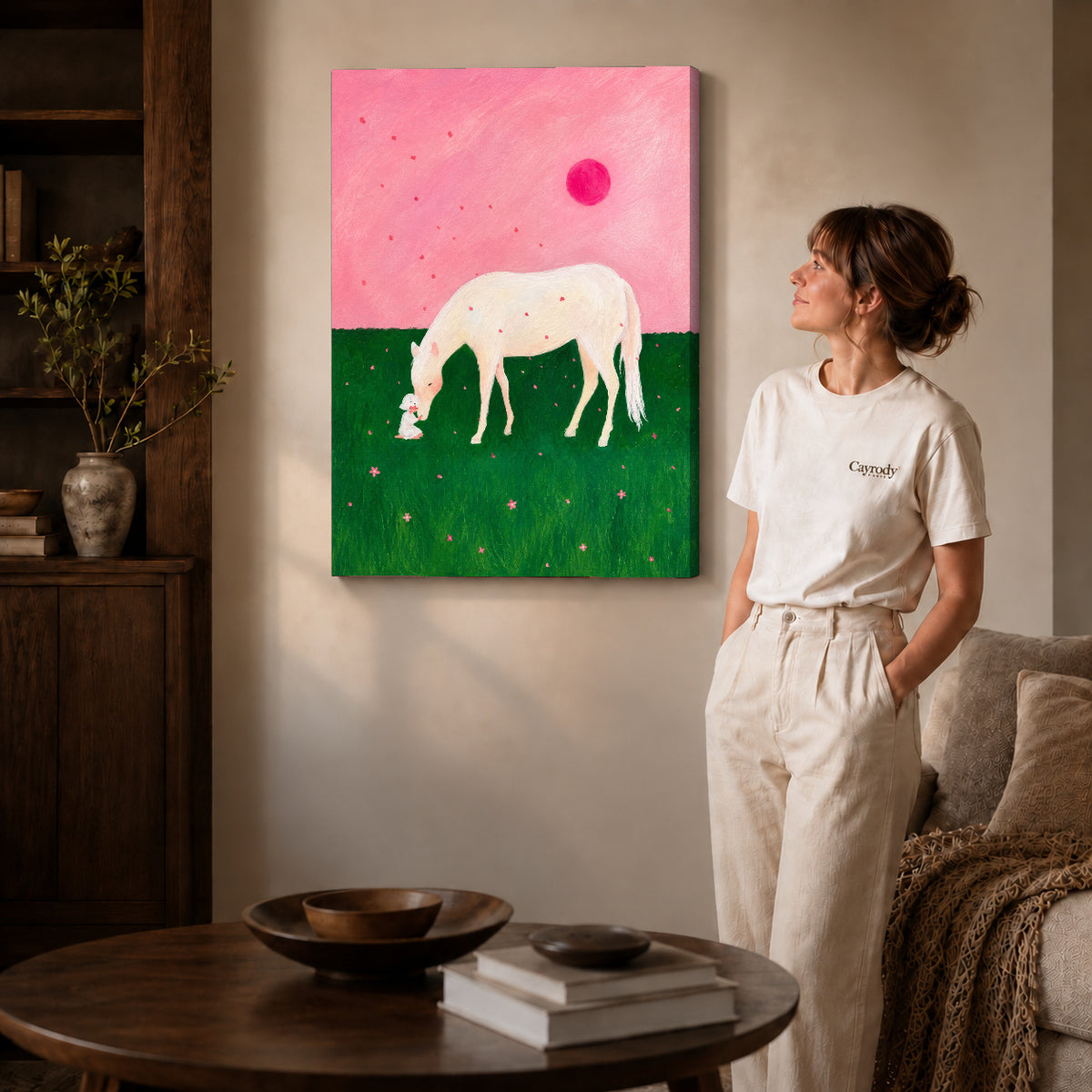 Gallery wrapped pink meadow horse canvas art with subtly shaded canvas edges beside a woman wearing cream clothing.