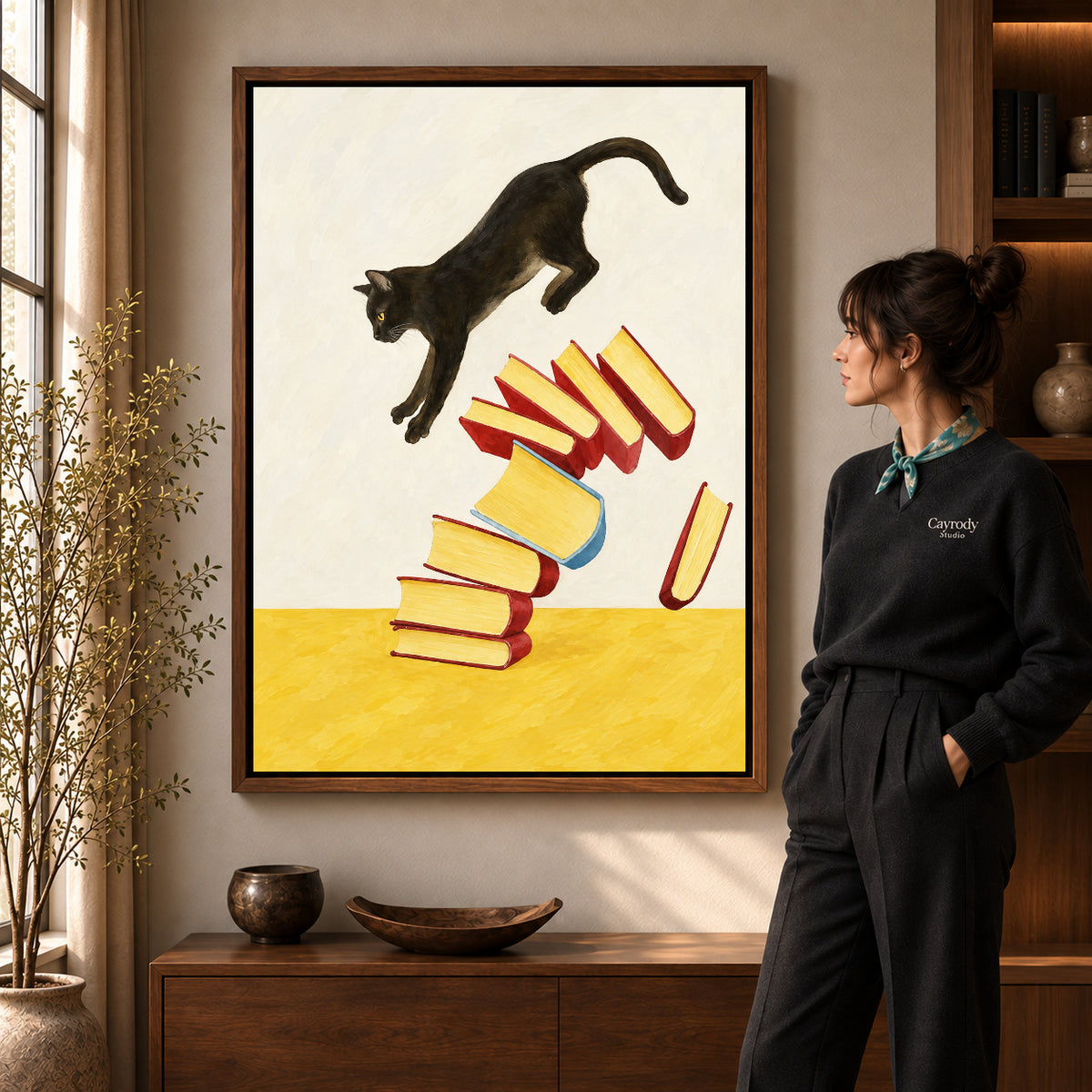 Leaping cat books canvas art in a walnut frame beside a woman in a warm living room.