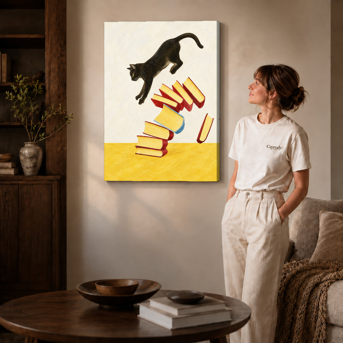 Gallery wrapped leaping cat books canvas art with subtly shaded canvas edges beside a woman wearing cream clothing.
