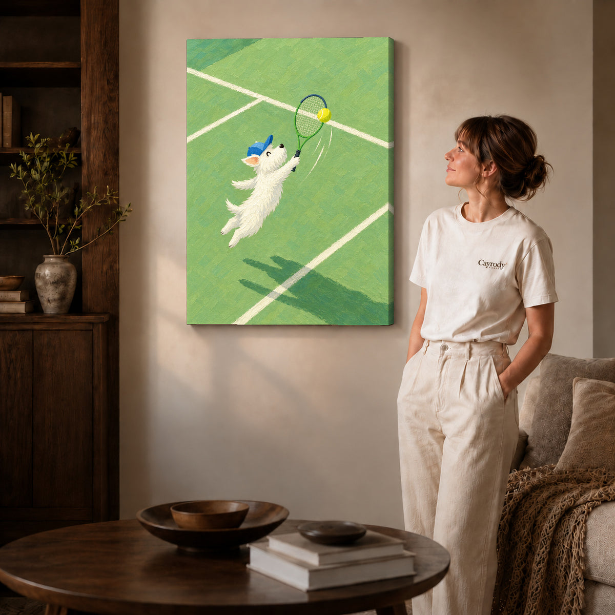 Gallery wrapped playful tennis dog canvas art with subtly shaded canvas edges beside a woman wearing cream clothing.
