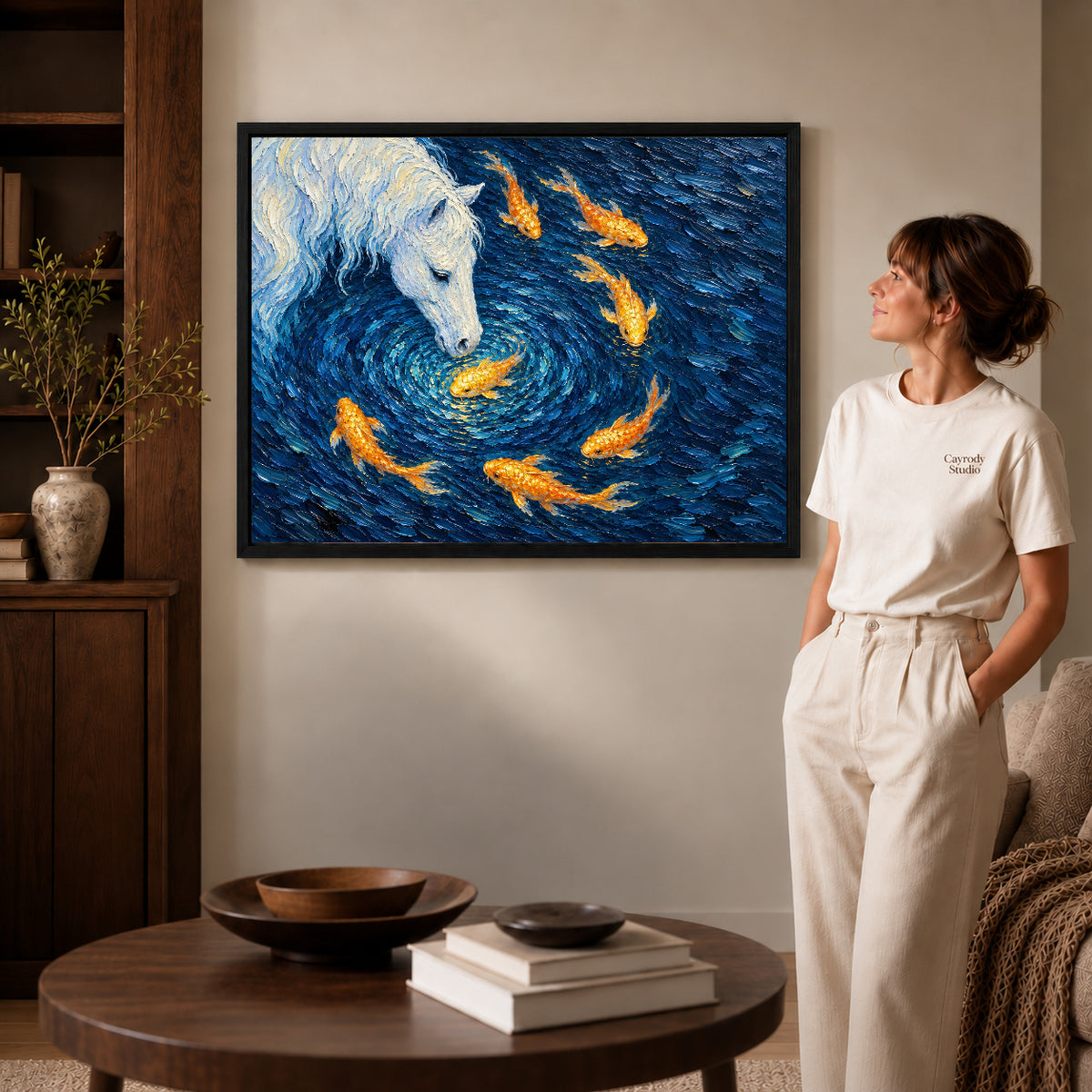 Black framed landscape white horse koi canvas art displayed beside a woman in a warm wood living room.