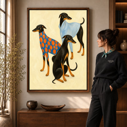 Stylish greyhound trio canvas art in a walnut frame beside a woman in a warm living room.