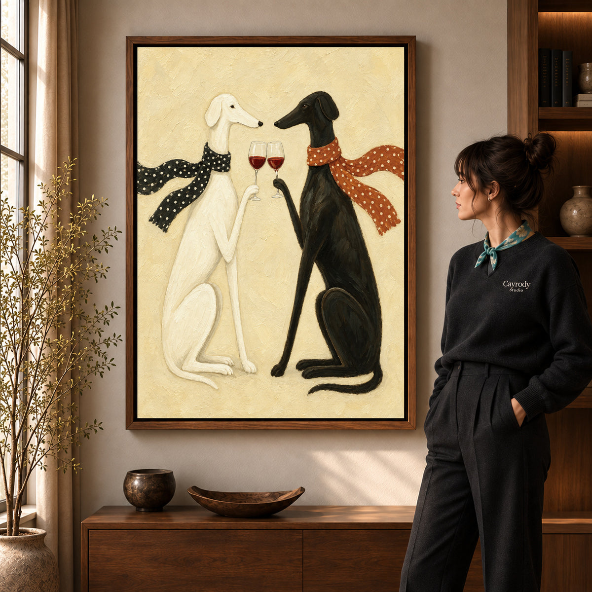Toasting greyhounds canvas art in a walnut frame beside a woman in a warm living room.