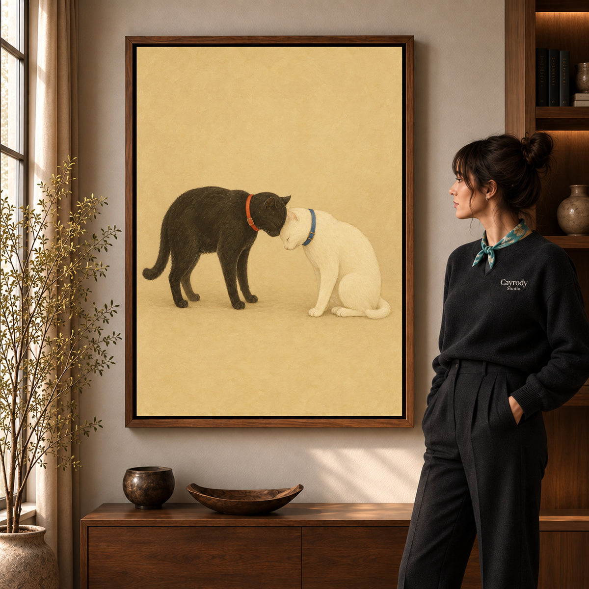 Tender cat companions canvas art in a walnut frame beside a woman in a warm living room.