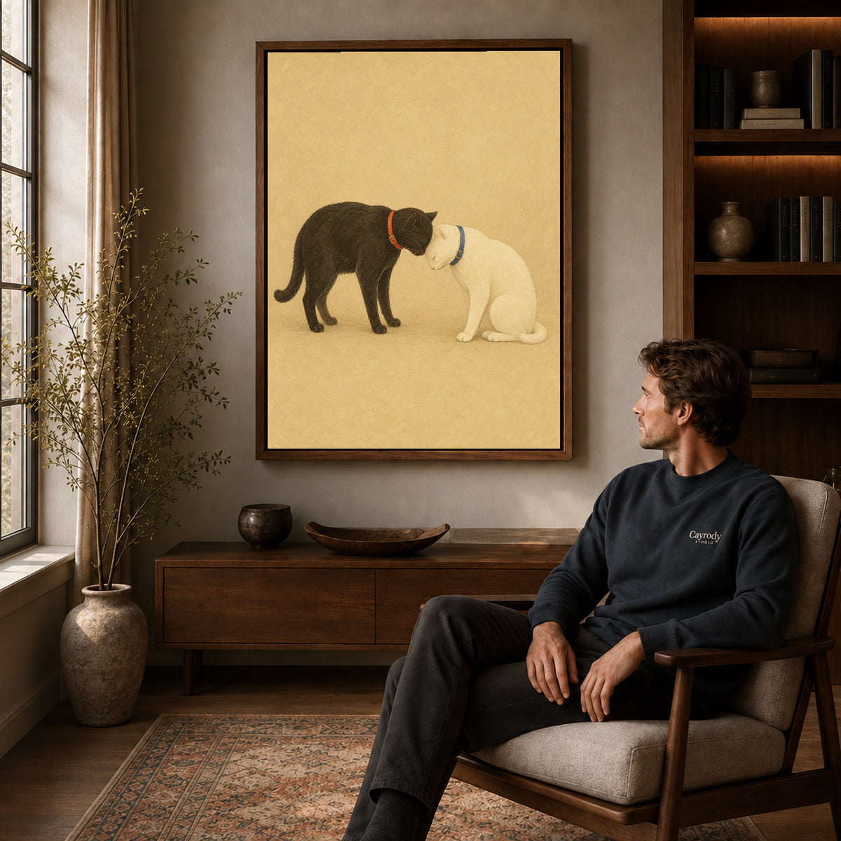 Walnut framed tender cat companions canvas art above a seated man in a cozy wood furnished living room.