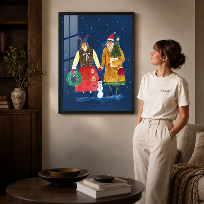 Folk Christmas canvas art in a black frame beside a woman and round wooden table.