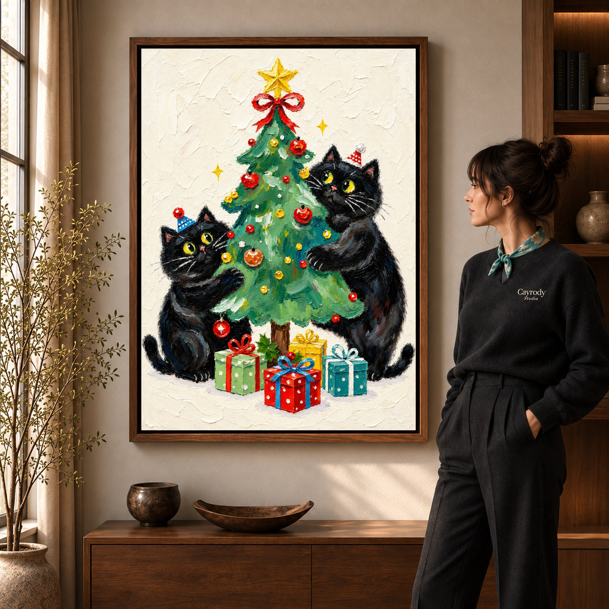 Christmas cats canvas art in a walnut frame beside a standing woman and wooden console.