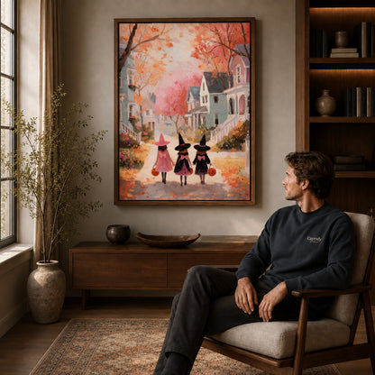 Little witches canvas art in a walnut frame above a console beside a seated man.