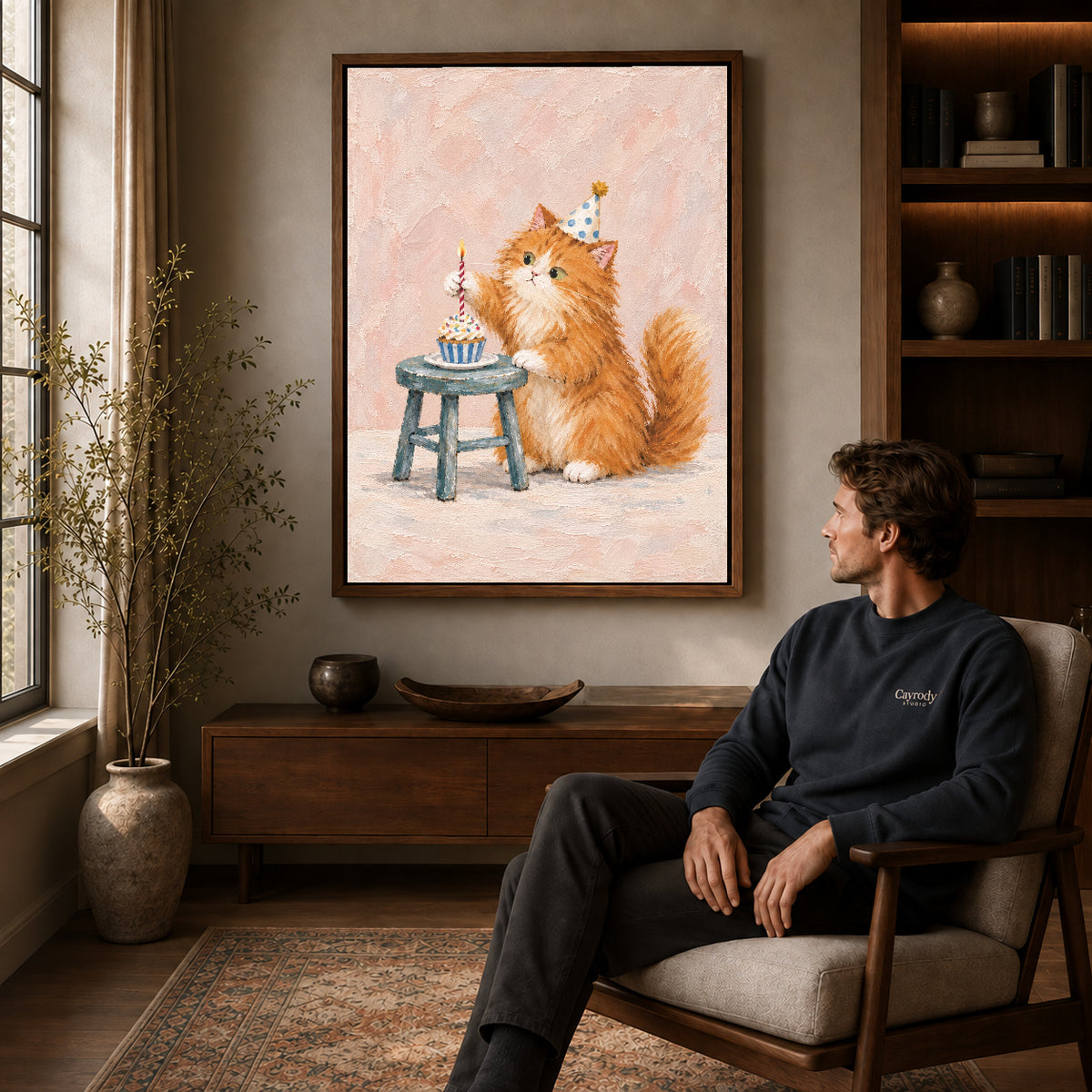 Birthday kitten canvas art in a walnut frame above a console beside a seated man.