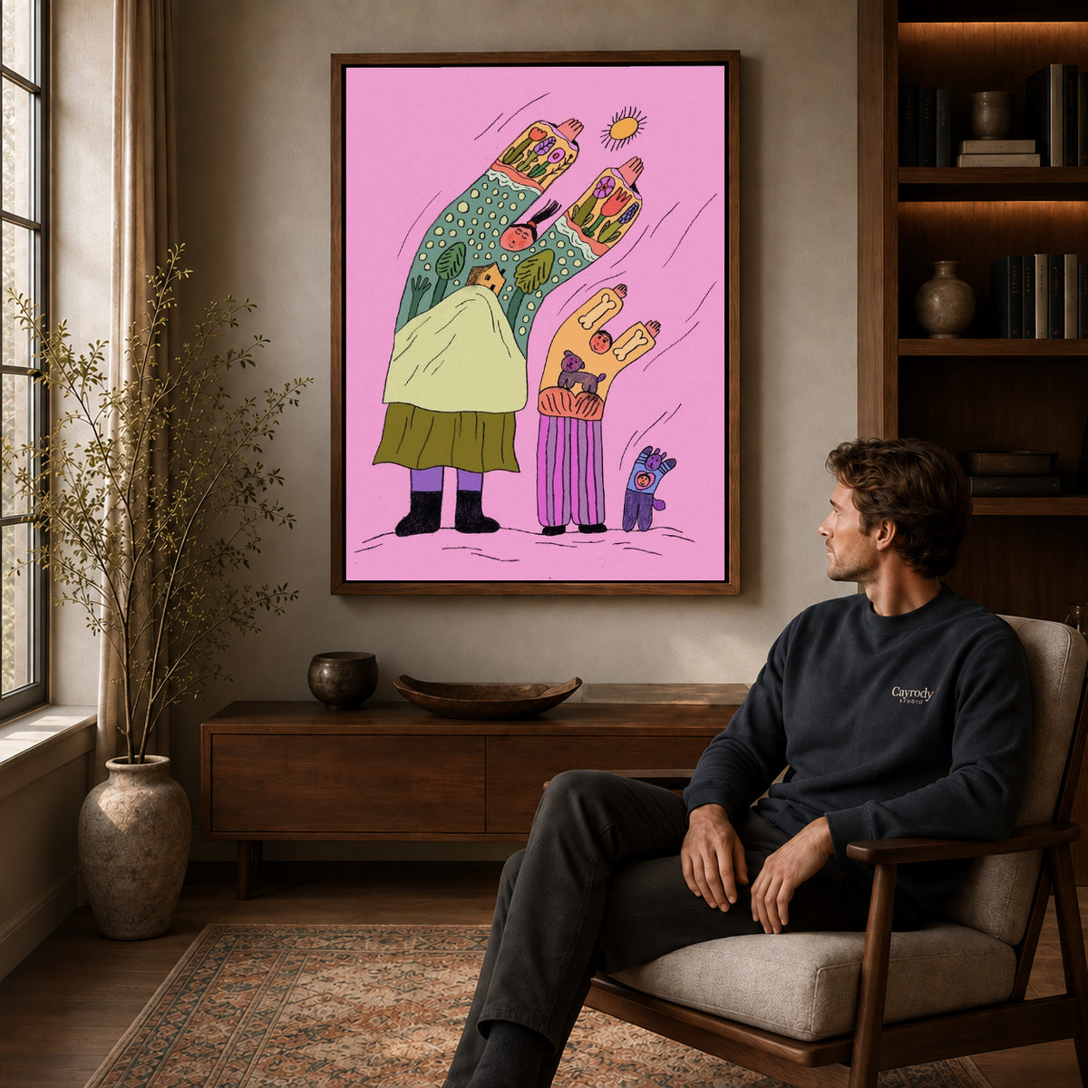 Folk family canvas art in a walnut frame above a console beside a seated man.