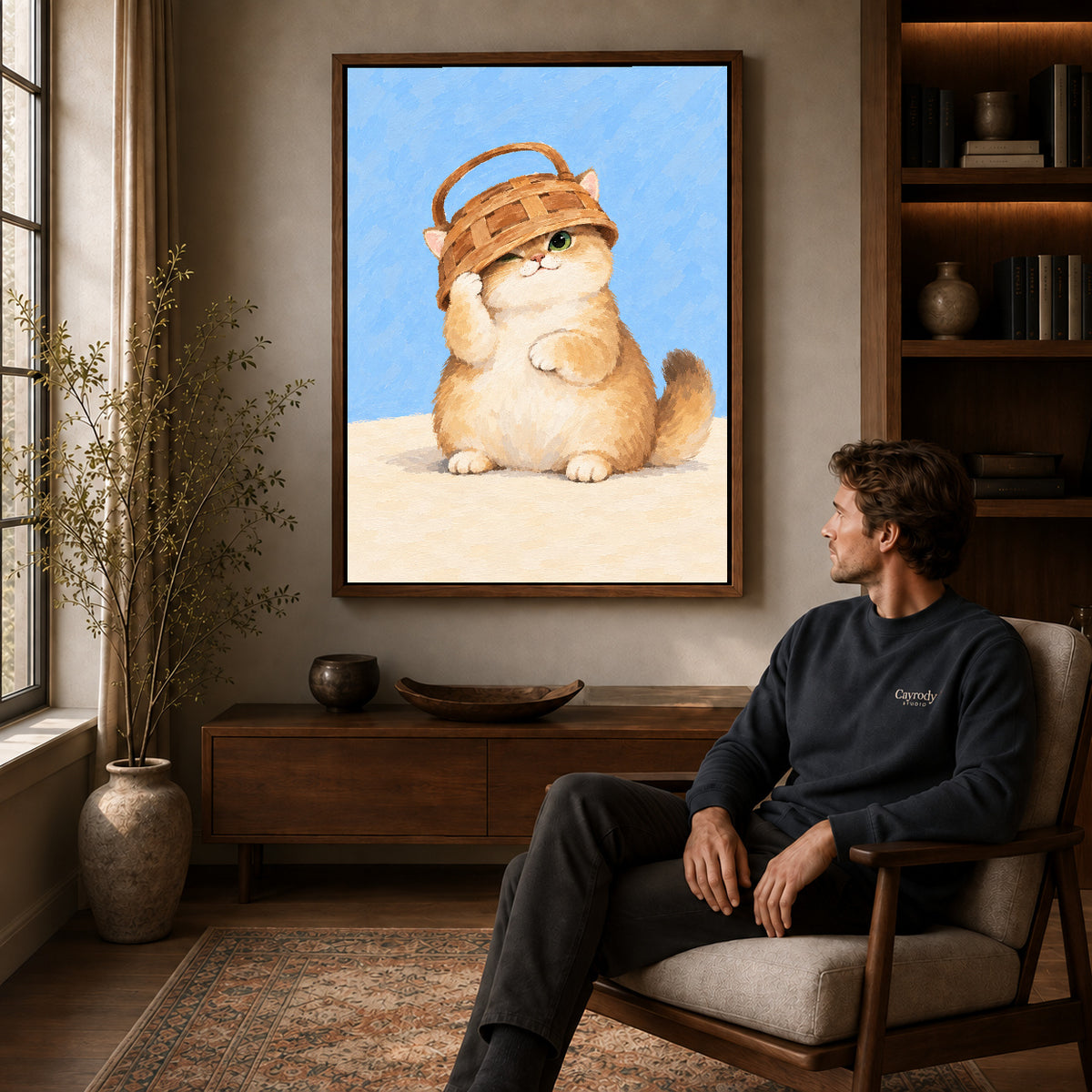 Basket kitten canvas art in a walnut frame above a console beside a seated man.