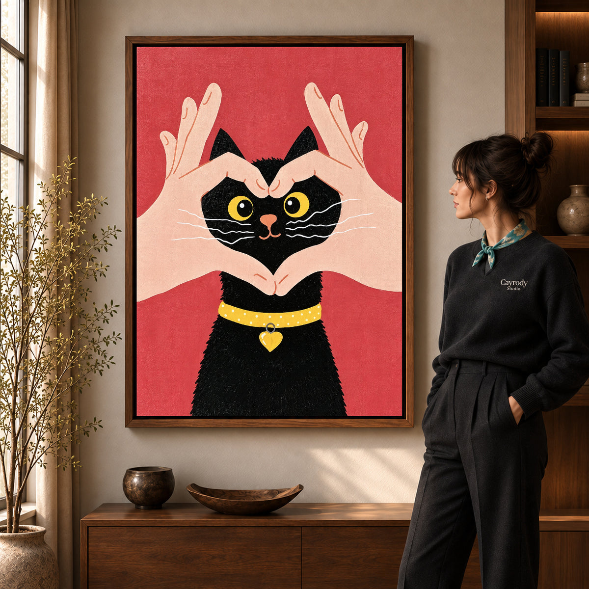 Heart kitten canvas art in a walnut frame beside a standing woman and wooden console.