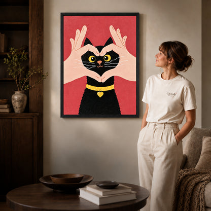 Heart kitten canvas art in a black frame beside a woman and round wooden table.