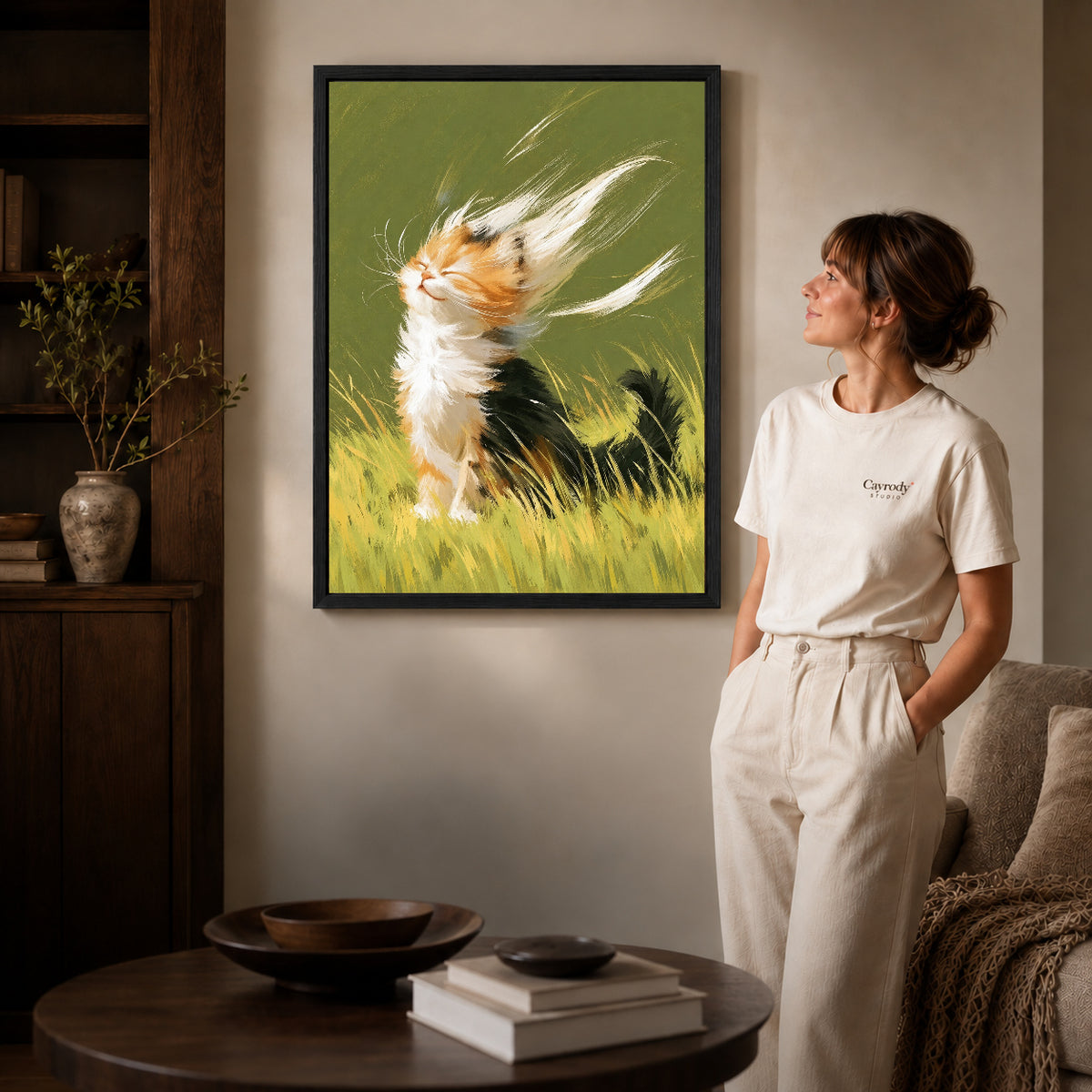 Calico kitten canvas art shown in the black frame option against a softly lit wall.